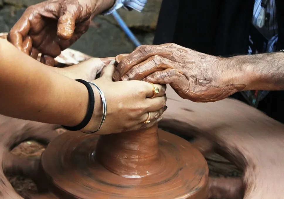 Hands shaping wet clay on a potter's wheel