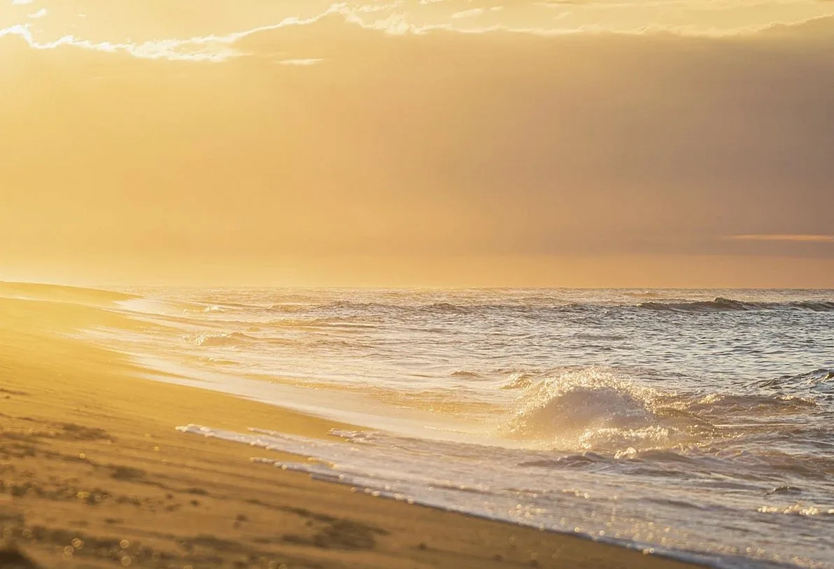 Golden light over breaking waves on a sandy beach
